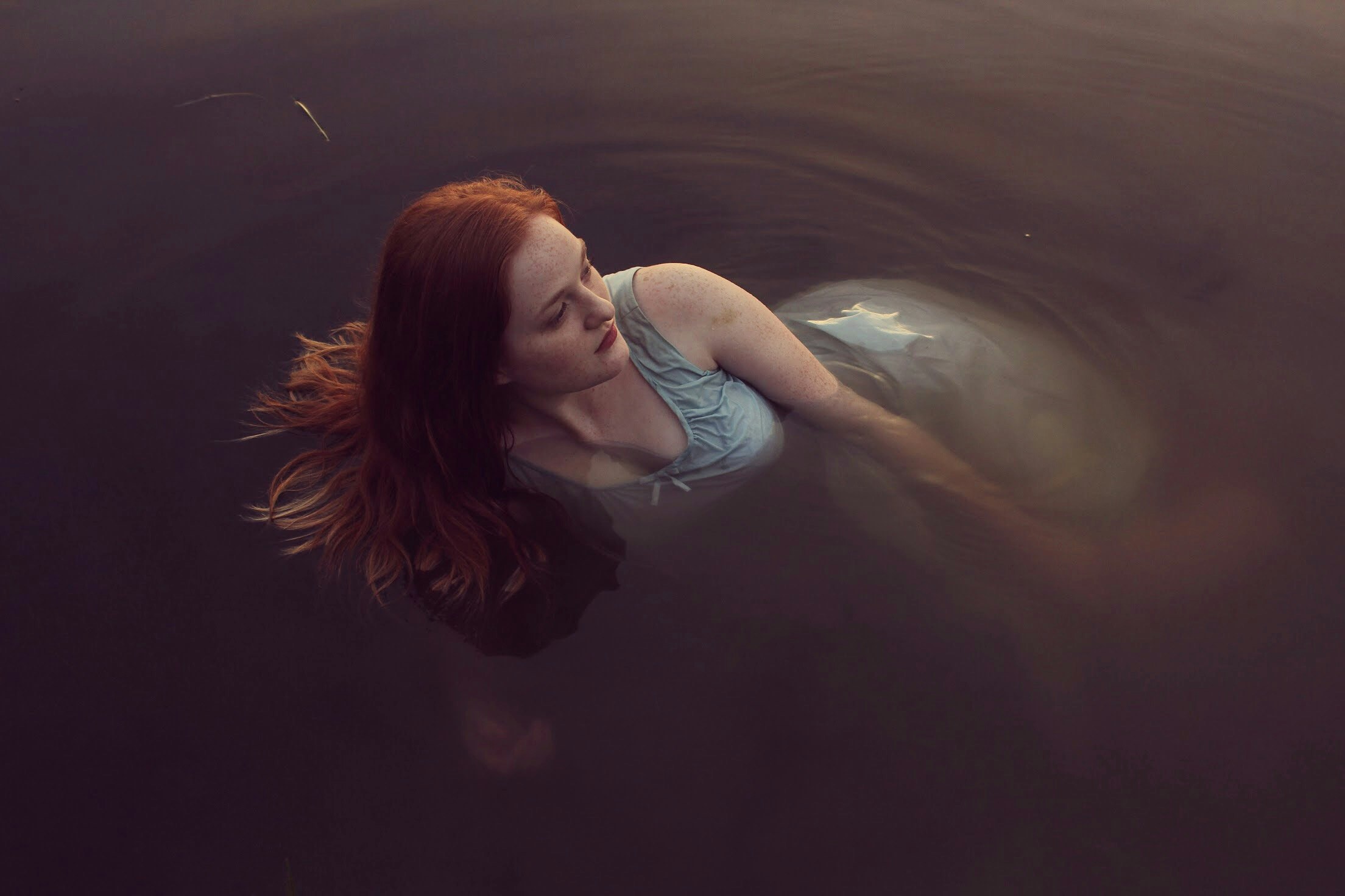 woman in gray tank dress lying on body of water during daytime